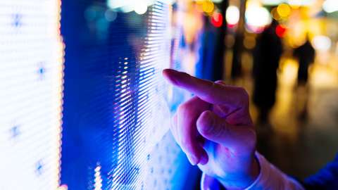 Dedo de um homem apontando para a tela de LED do preço do mercado de ações à noite